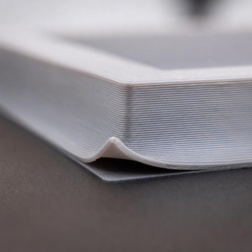 Detalhe de um canto de peça impressa em 3D descolando e curvando para cima