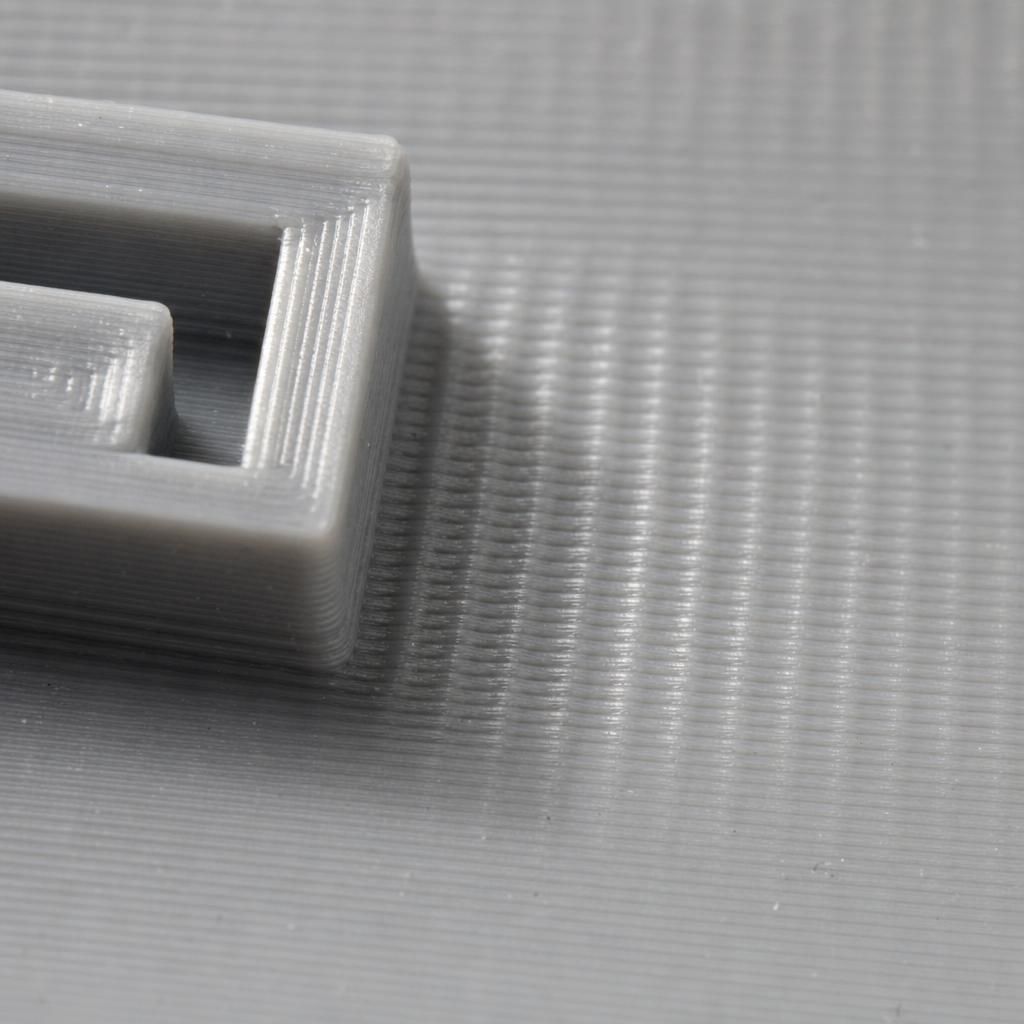 Macro do padrão de ghosting na impressão 3D, ondas repetidas atrás de um relevo na parede da peça